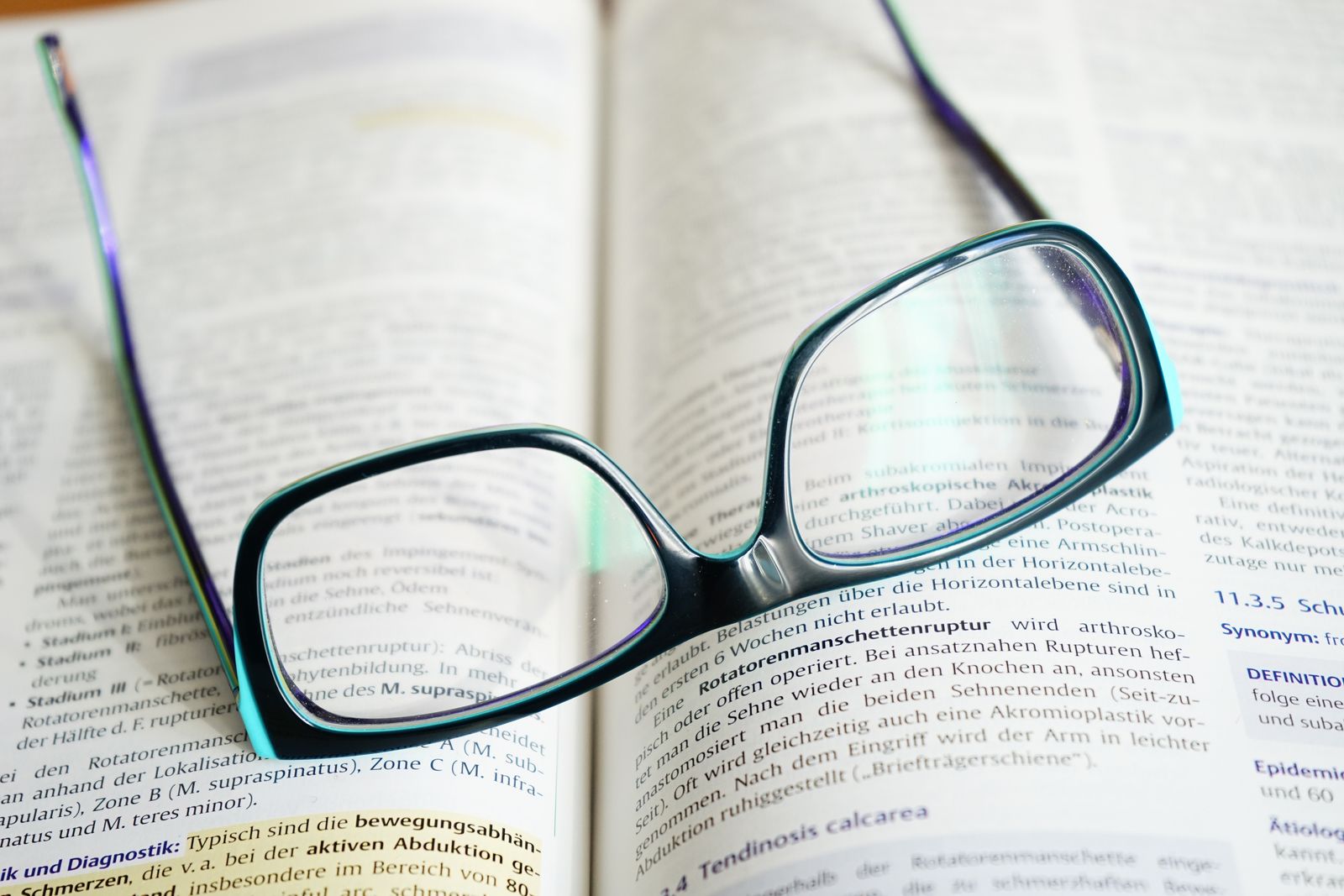 Des lunettes de lecture reposant sur un manuel ouvert, symbolisant l'étude et le savoir.
